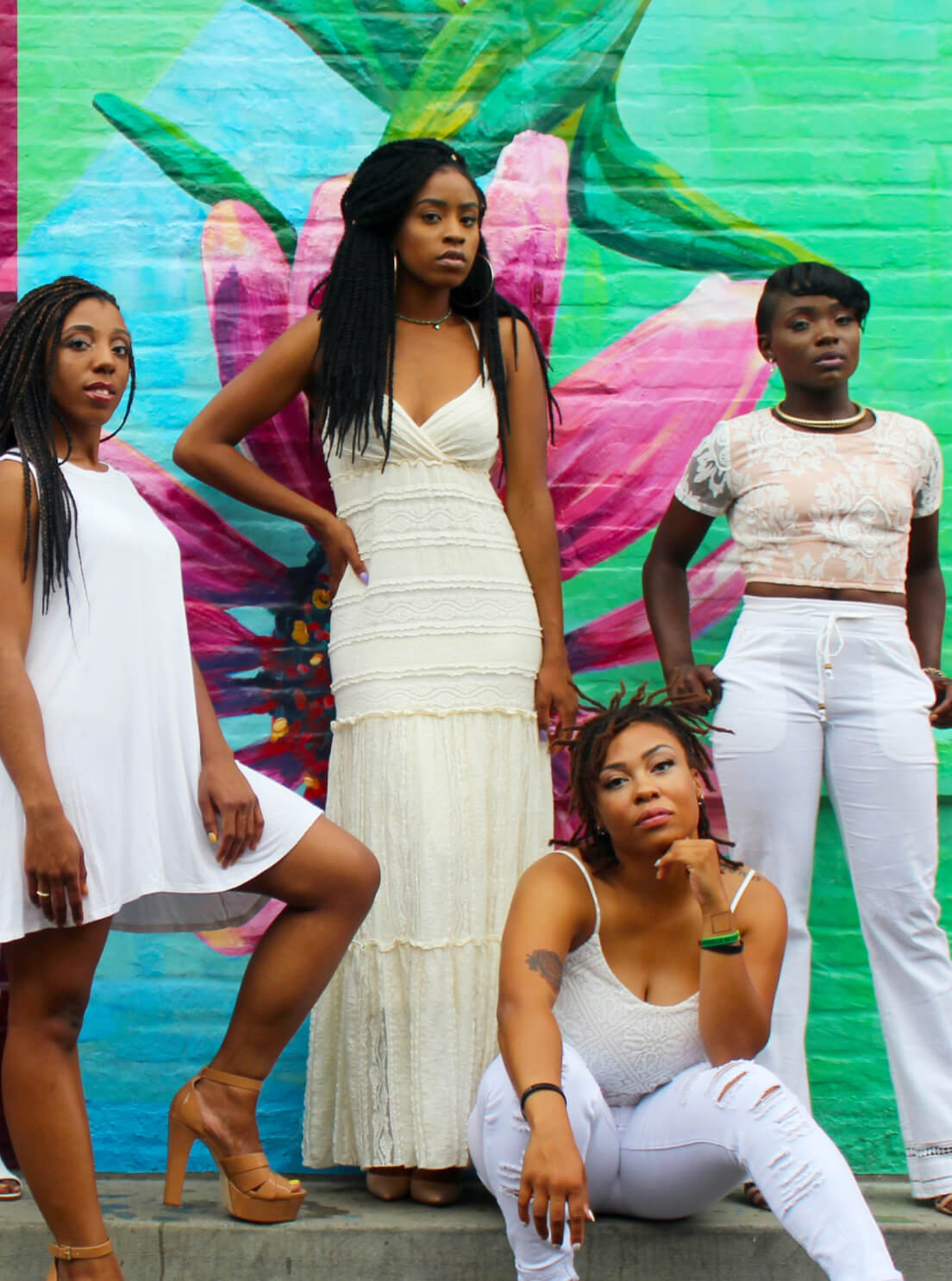 A group of women of color in front of a colorful painted wall