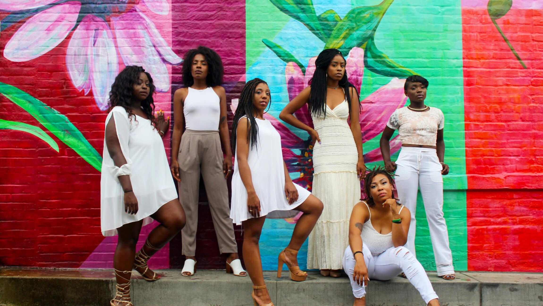 A group of women of color in front of a colorful painted wall